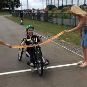 Jess Green, 18, crosses the finish line of her marathon, with her teacher and godmother holding the finish line